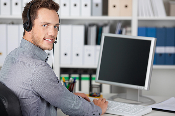 A Singapore-based IT support specialist wearing a headset, remotely assisting a client via computer.