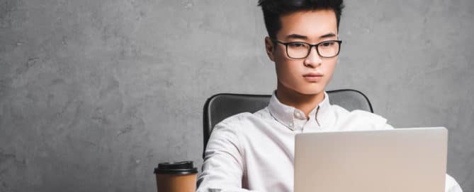 IT manager sitting at table while typing on laptop concept image for outsourcing IT projects