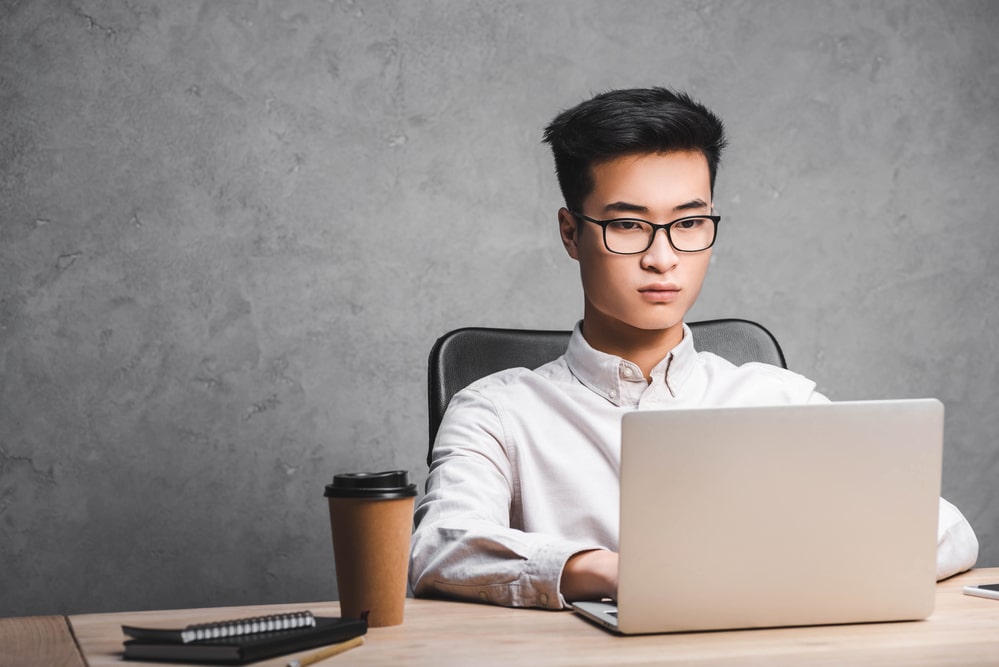 IT manager sitting at table while typing on laptop concept image for outsourcing IT projects