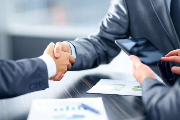 Business partners sealing a deal with a handshake, symbolizing a partnership in financial systems consulting.