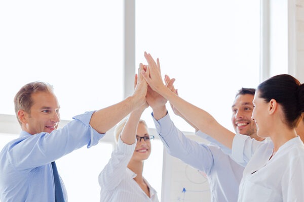 Enthusiastic team at a financial firm celebrating success with high fives