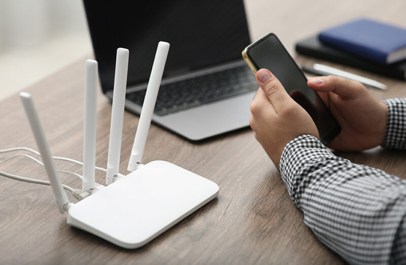 Man using smartphone and laptop to connect to a network, illustrating wifi design best practices