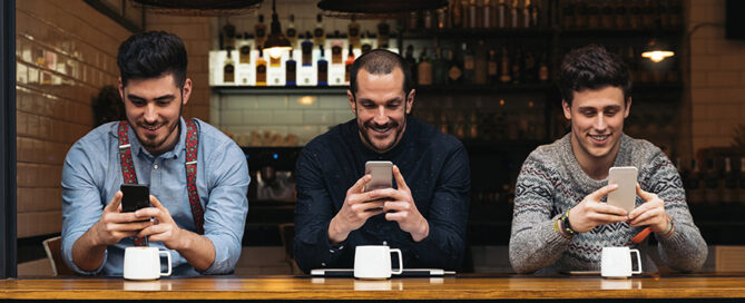 Three men enjoying free Wi-Fi at a restaurant, illustrating how to update your restaurant WiFi to enhance customer experience