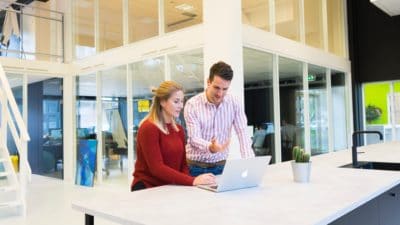 it support helping woman with laptop in a tech lounge